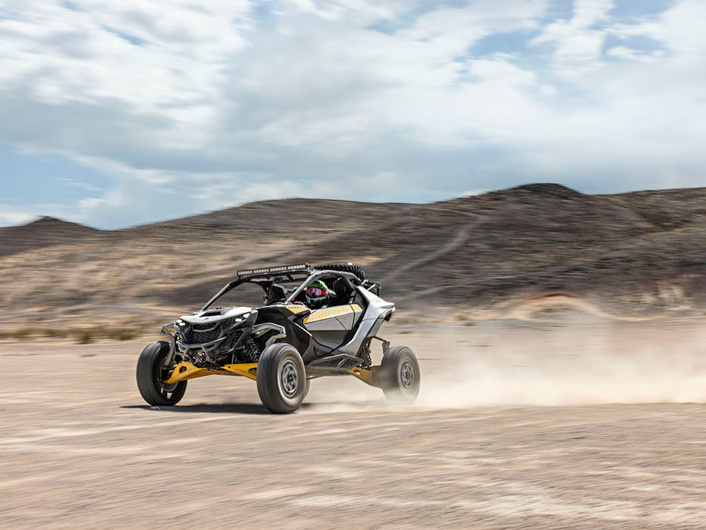 Off-road vehicle speeding on a desert landscape with a clear sky.